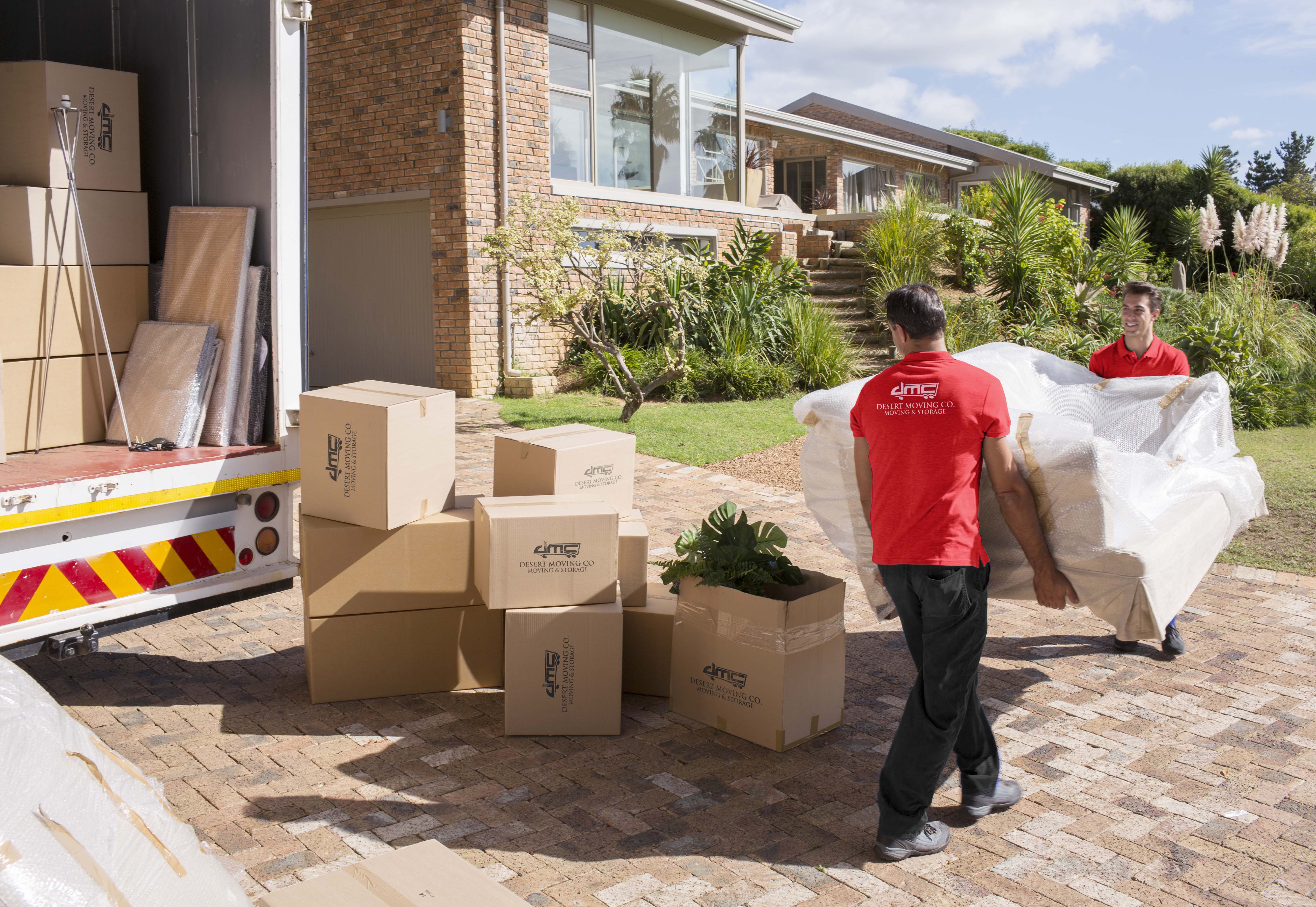 Two Desert Moving movers unloading boxes and wrapped items at home